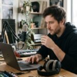 Independent musician reviewing music metadata on a laptop in a home studio
